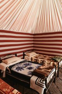 a room with three beds in a tent at Wadi Rum Backpacker Camp in Wadi Rum