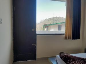 Bhowāli的住宿－New Sameer Hotel，窗户房间里一扇黑色的门