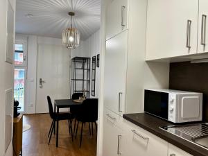 Il comprend une cuisine équipée d'un four micro-ondes et d'une table avec des chaises. dans l'établissement sHome Apartments Graz - Self-Check-in & free parking, à Graz