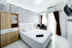 a bedroom with a white bed and a brick wall at Apartemen Riverview Cikarang by Room PDL 99 in Bekasi