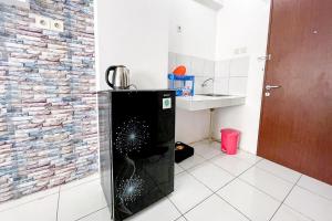 a black refrigerator in a room with a brick wall at Apartemen Riverview Cikarang by Room PDL 99 in Bekasi