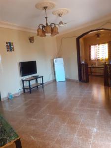 a living room with a tiled floor and a television at Sunshine Villa House in Brufut