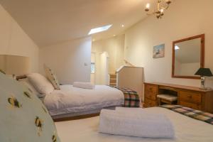 a bedroom with two beds and a desk and a mirror at Woodpeckers Barns in Liskeard