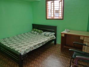 a green bedroom with a bed and a desk at KKA RESIDENCY in Coimbatore