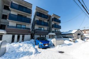 a blue car parked in the snow in front of a building at SERAPHIC 千歳MS101 in Chitose