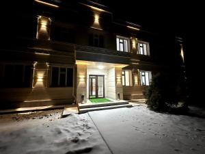 una casa de noche con nieve delante en Ак-Бата, en Alamedin