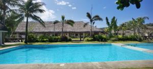 a swimming pool in front of a house with palm trees at Ikani Surf Resort in Pagudpud