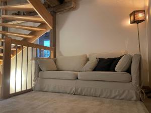 un divano bianco in un soggiorno con scala di La grange de Sophie a Berstett