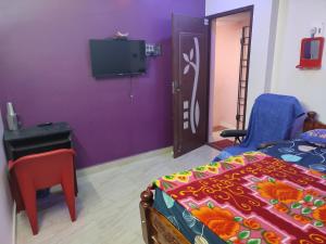 sypialnia z łóżkiem i telewizorem na fioletowej ścianie w obiekcie Blue Diamond w mieście Ćennaj