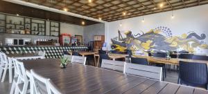 a restaurant with wooden tables and chairs and a mural at Ikani Surf Resort in Pagudpud