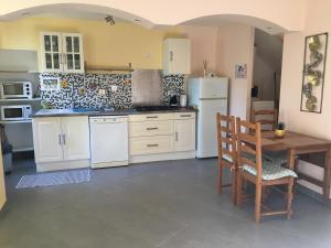 una cocina con electrodomésticos blancos, mesa y sillas en studio avec terrasse de 20 m2, en Vidauban