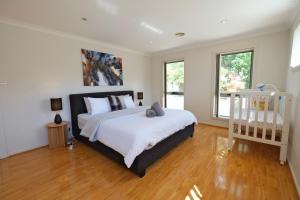 Canberra Comfort Family Cottage with 5 Beds& Pet Welcoming في Hall: غرفة نوم بسرير كبير مع شراشف بيضاء