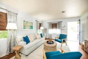 a living room with a white couch and blue chairs at Casa Posada - So Close You Can Hear the Waves Historic Beach Cottage w Beach Gear in Anna Maria
