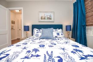 a bedroom with a blue and white bed and blue curtains at Casa Posada - So Close You Can Hear the Waves Historic Beach Cottage w Beach Gear in Anna Maria