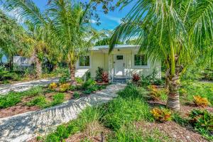 eine Palme vor einem Haus in der Unterkunft Casa Posada - So Close You Can Hear the Waves Historic Beach Cottage w Beach Gear in Anna Maria