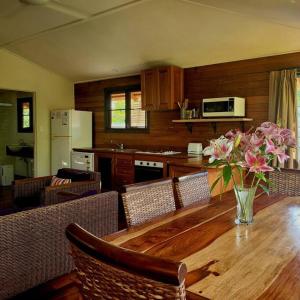a kitchen with a wooden table with a vase of flowers at Mission Beachfront Cottage in Mission Beach