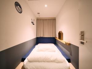 a small bedroom with two beds in it at Hotel Plus Hostel TOKYO KAWASAKI in Kawasaki