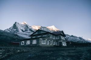 an old house with snow covered mountains in the background at Mountain Lodges of Nepal - Kongde in Kongde