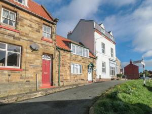 an old brick building with a red door on a street at Newton Cottage in Whitby