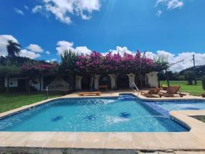 uma piscina num quintal com flores cor-de-rosa em Kandire Posada Rural em San Ygnacio