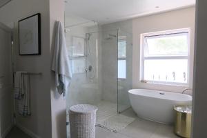 a white bathroom with a tub and a shower at Villa du Soleil Plettenberg Bay in Plettenberg Bay