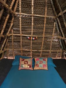 dos almohadas sentadas en una cama en un techo de paja en Nebula Nest Cafe & Hostel, en Auroville
