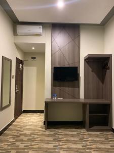 Bless Hotels في Sintang: غرفة بها مكتب وتلفزيون على الحائط