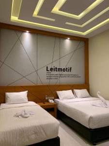 Bless Hotels في Sintang: سريرين في غرفة مع علامة على الحائط