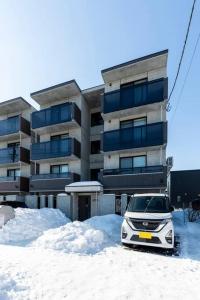 un coche aparcado en la nieve frente a un edificio en SECLUSION 千歳MS102, en Chitose
