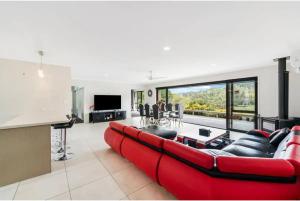 a living room with a red couch and a table at Luxury Modern 3-BDR Oasis in Kumeu