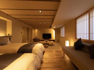 a bedroom with two beds and a tv and a couch at Hotel Kazurabashi in Miyoshi
