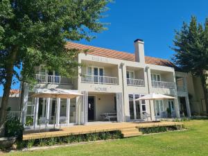 un grand bâtiment blanc avec des parasols en face de celui-ci dans l'établissement Boschenmeer House, à Paarl