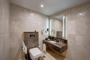 a bathroom with a sink and a toilet and a mirror at Vintage Grand Hotel - Formerly Ghaya Grand Hotel in Dubai