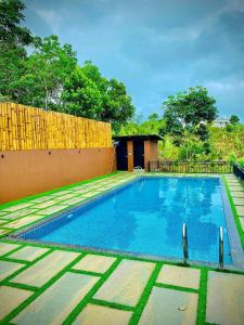 a swimming pool in a yard next to a fence at KAP KOROME VILLAGE RESORT in Koroth