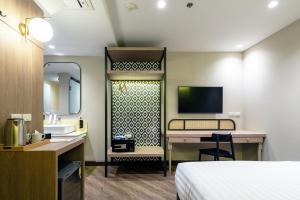 ein Hotelzimmer mit einem Bett, einem Schreibtisch und einem TV in der Unterkunft The Cotton Saladaeng Hotel in Bangkok