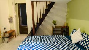 ein Schlafzimmer mit einem Bett mit einer blau-weißen karierten Decke in der Unterkunft 1967 Homestay in Ho-Chi-Minh-Stadt