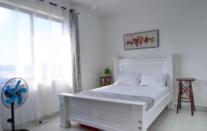 a white bedroom with a white bed and a window at AC, 1 BR, 43 inch Smart TV, Hot shower- LightHouse in Mombasa