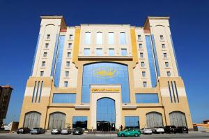 un edificio alto con coches estacionados frente a él en Helat Hotel en Al Khobar
