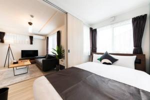 a bedroom with a large bed and a living room at SERENADE in Chitose