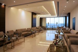 a waiting room with couches and tables and windows at Helat Hotel in Al Khobar