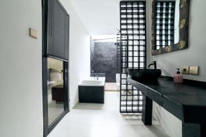Un baño con un lavabo negro y un espejo. en Cantik ArtVilla, en Uluwatu 13 fotos más