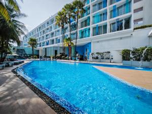 a large swimming pool in front of a building at Hotel Baraquda Heeton Pattaya by Compass Hospitality in Pattaya