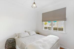 a white bedroom with a bed and a window at Central and Affordable - Cute Art Deco in Gisborne