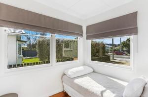 a white room with a bed and two windows at Central and Affordable - Cute Art Deco in Gisborne