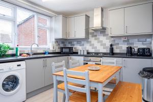 a kitchen with a wooden table and white cabinets at Private immaculate contractor and leisure stay with large driveway in Birmingham