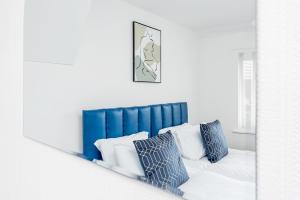 espejo que refleja una cama con cabecero azul y almohadas en Private immaculate contractor and leisure stay with large driveway, en Birmingham