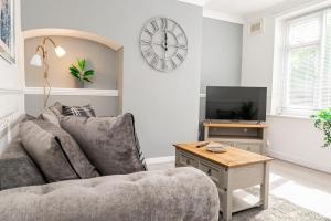a living room with a couch and a clock on the wall at Private immaculate contractor and leisure stay with large driveway in Birmingham