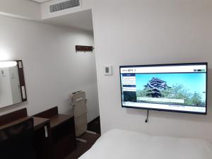 una TV a schermo piatto appesa a un muro in una camera di Hotel Alpha-One Matsue a Matsue