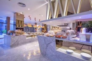 ein Restaurant mit Buffet mit Menschen, die Essen zubereiten in der Unterkunft Balcony Seaside Sriracha Hotel & Serviced Apartments in Si Racha