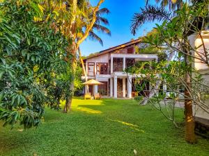 a house with a green yard with trees at Villa Ema in Galle
